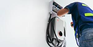 Best Level 2 Ev Charger An electrician installing a wall-mounted charging station, illustrating professional home installation for the best level 2 EV charger.